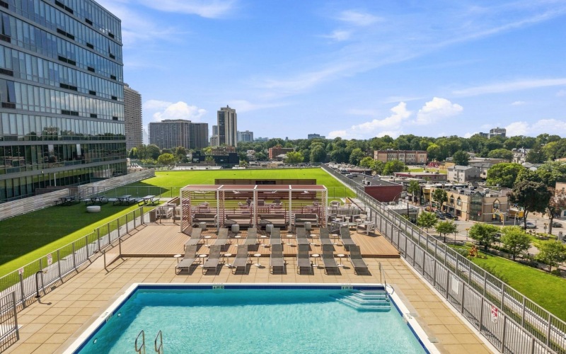 Outdoor amenity deck with pool, lounge seating, and movie theater