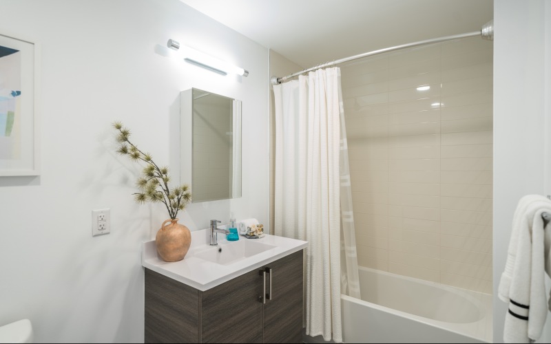 Apartment bathroom with tab, curtains, towel, and cabinet